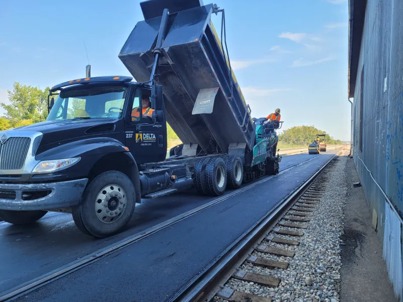 Engineer holding blueprint with backhoe background
